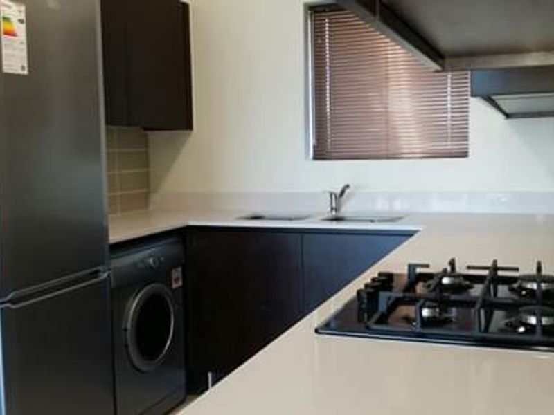 Modern kitchen featuring dark cabinetry, stone countertops, a gas hob, and a tiled splashback with a functional layout.