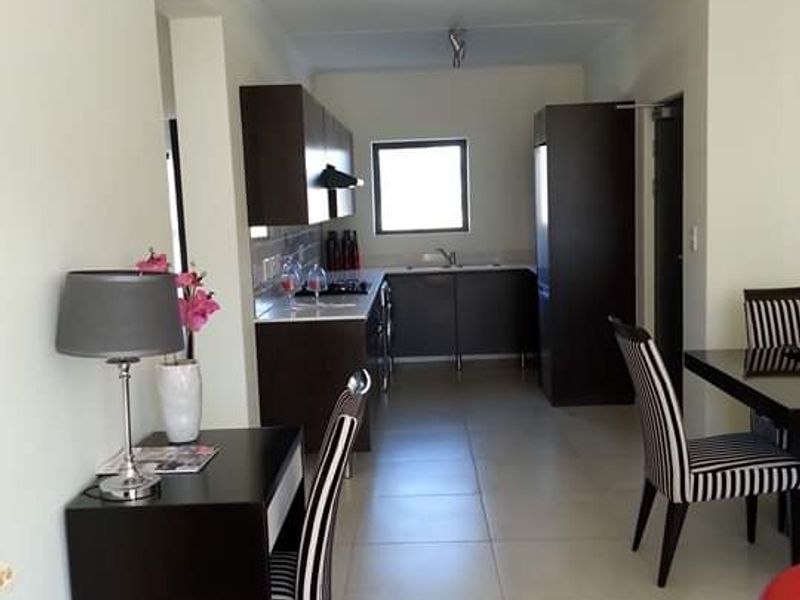 Open-plan living and kitchen area featuring dark cabinetry, tiled flooring, and a functional layout with integrated kitchen appliances.