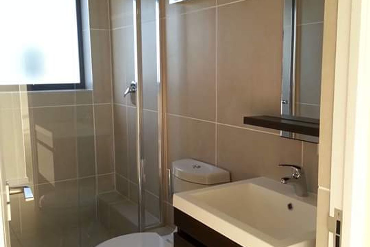 A modern, well-maintained bathroom featuring a glass shower enclosure, a wall-mounted vanity unit, and neutral floor-to-ceiling wall tiles.
