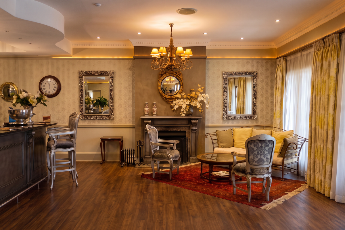Elegant living room featuring a built-in bar, a classic fireplace, crown molding, and warm hardwood flooring, creating a sophisticated and inviting atmosphere.