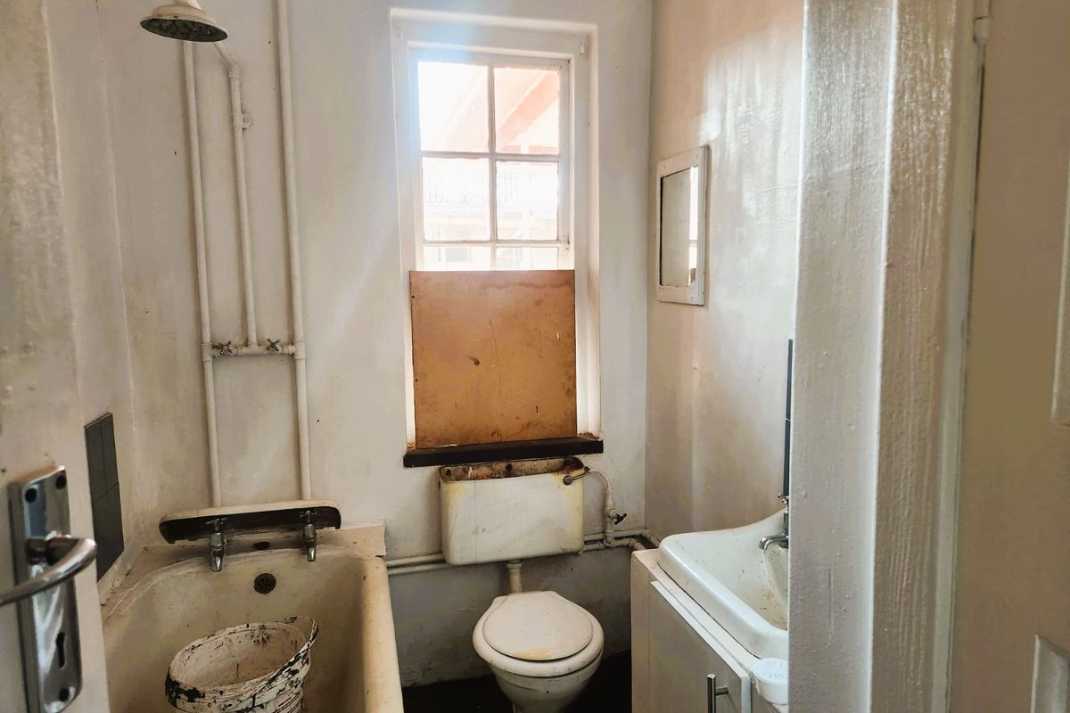 A dated bathroom featuring a bathtub, toilet, and vanity basin, requiring significant renovation and cosmetic updates to restore functionality and appeal.