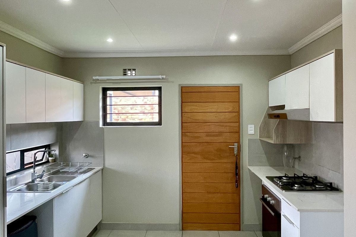 Modern kitchen featuring white cabinetry, stone countertops, gas hob, built-in oven, and tiled flooring with recessed lighting.