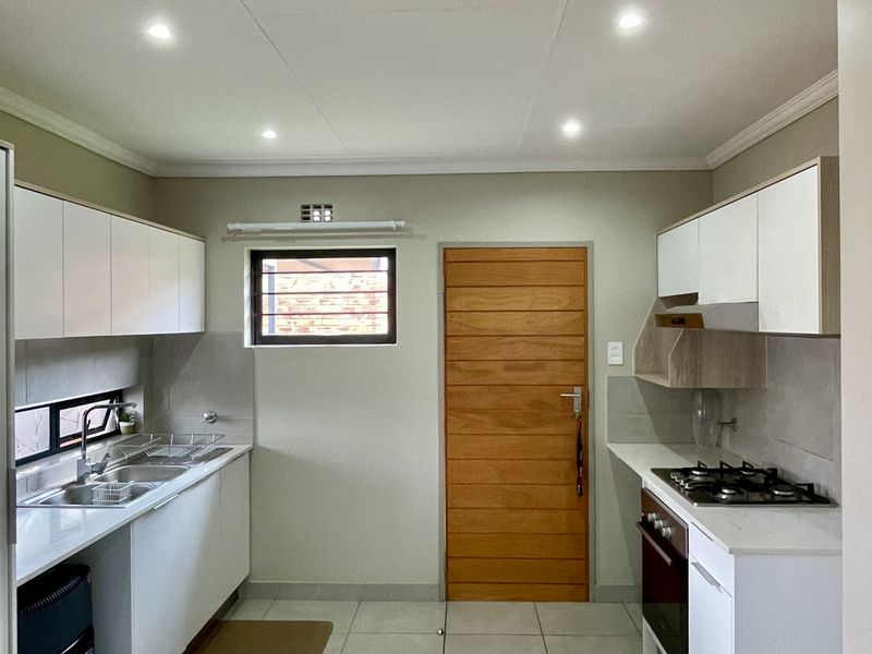 Modern kitchen featuring white cabinetry, stone countertops, gas hob, built-in oven, and tiled flooring with recessed lighting.