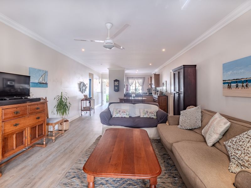 Spacious open-plan living and dining area featuring laminate flooring, crown molding, and a ceiling fan, flowing into the kitchen space.