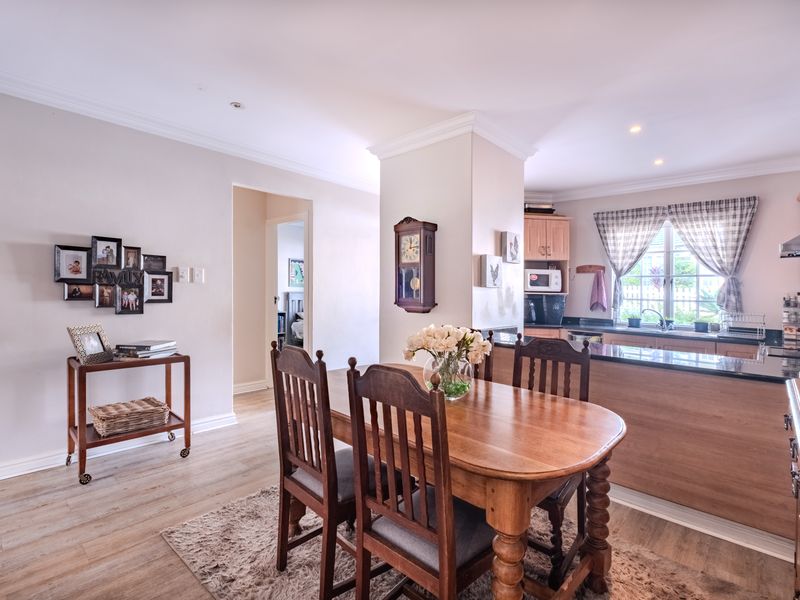 Open-plan dining area and kitchen featuring laminate flooring, granite countertops, and wooden cabinetry, creating a functional and connected living space.