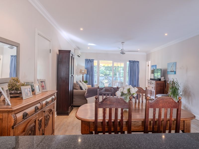 Spacious open-plan living and dining area featuring laminate flooring, recessed lighting, and sliding glass doors leading to an outdoor space.