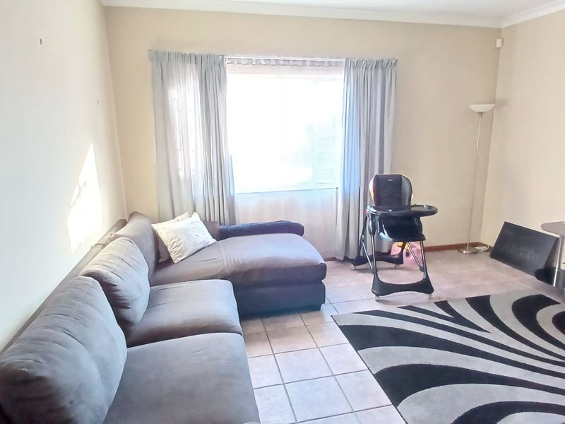A functional living room featuring tiled flooring and neutral wall finishes, offering a blank canvas for potential interior updates.