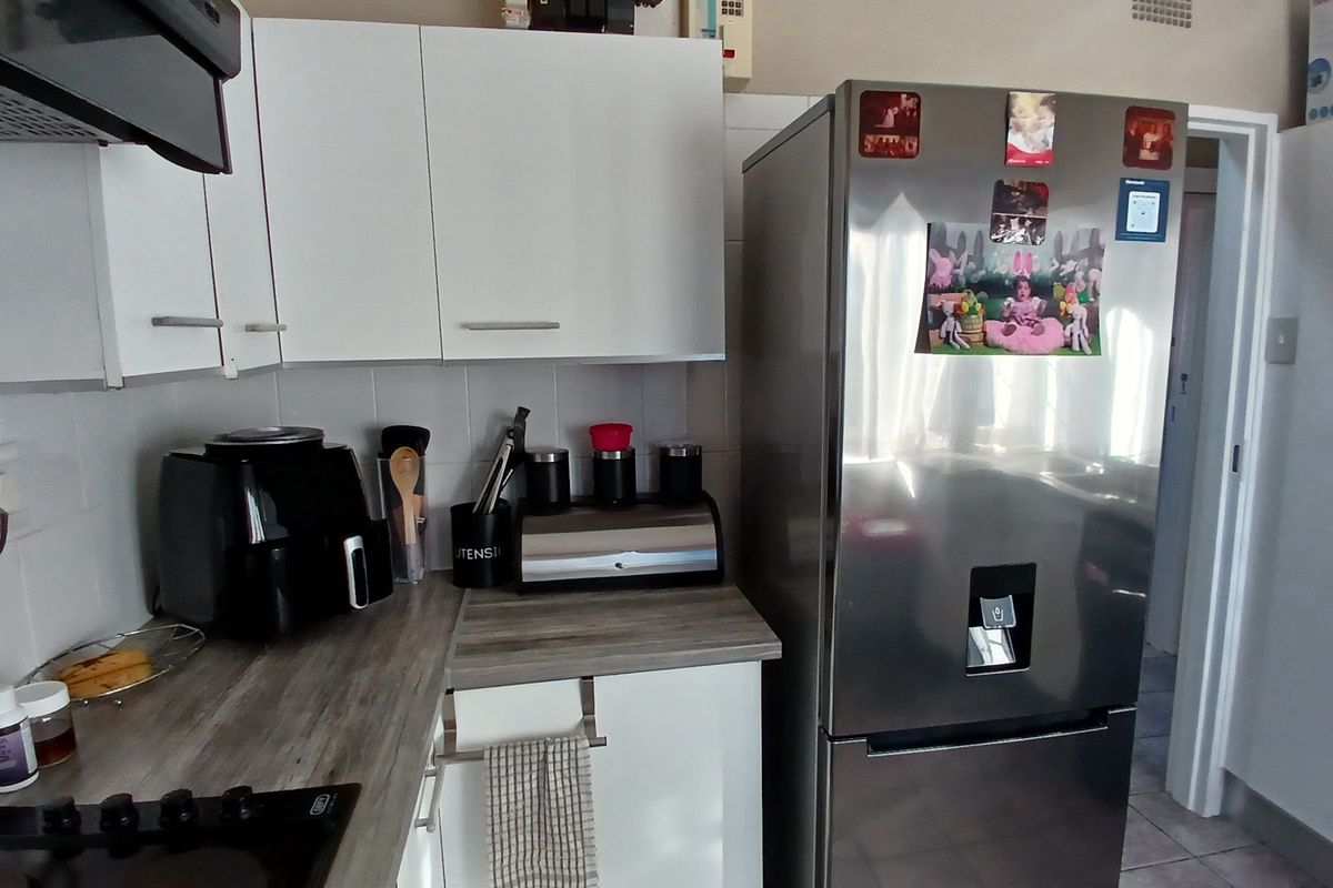 A functional kitchen featuring white cabinetry, a wood-look laminate countertop, tiled backsplash, and a built-in electric hob with an extractor fan.