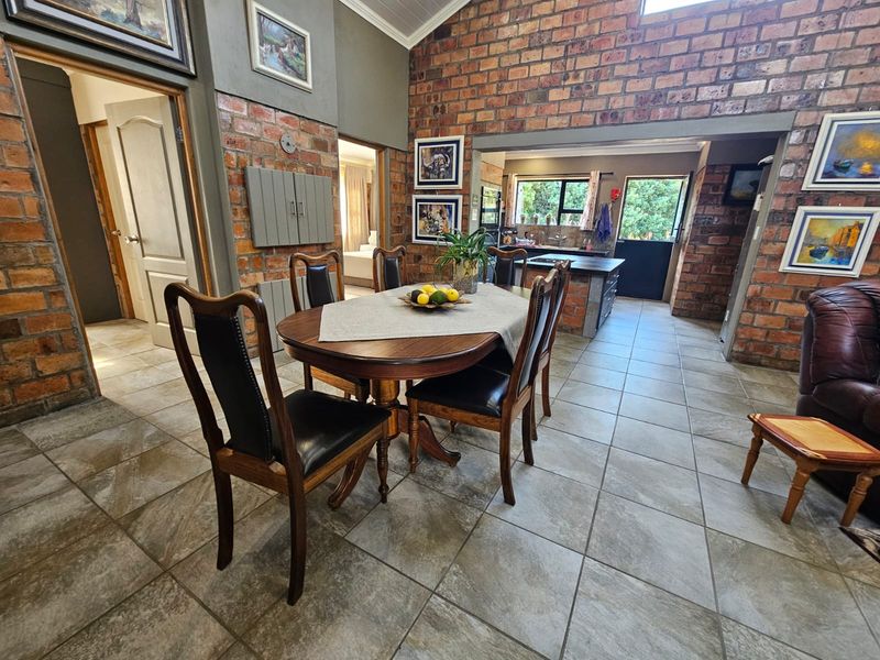 Spacious open-plan dining and kitchen area featuring rustic exposed brick walls, vaulted ceilings, and durable tiled flooring with a functional kitchen island.