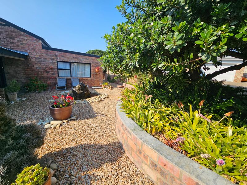 A well-maintained garden area featuring gravel landscaping, a curved brick retaining wall, and an exposed brick exterior facade.