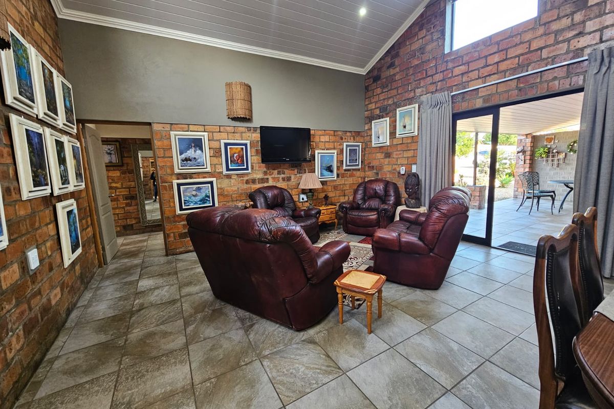 Spacious living room featuring exposed brick walls, vaulted ceilings, tiled flooring, and large sliding glass doors providing access to the outdoor patio area.