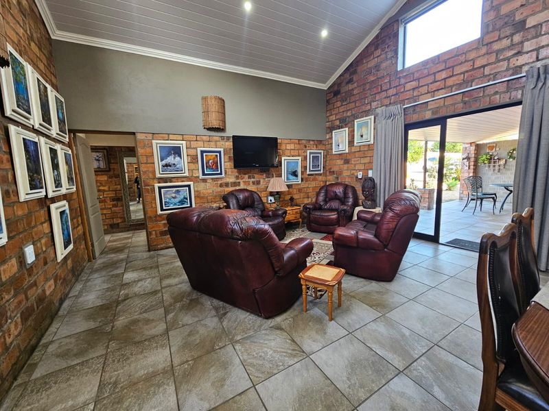 Spacious living room featuring exposed brick walls, vaulted ceilings, tiled flooring, and large sliding glass doors providing access to the outdoor patio area.