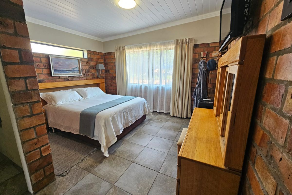 A bedroom featuring exposed brick walls, tiled flooring, and a tongue and groove ceiling, providing a rustic aesthetic.
