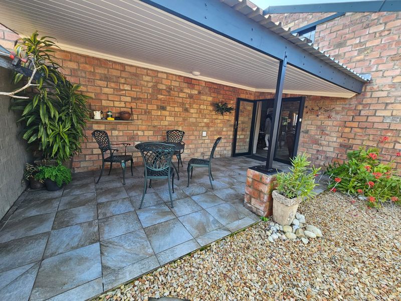 A covered outdoor patio area featuring exposed brick walls, tiled flooring, and direct access to the interior through double glass doors.