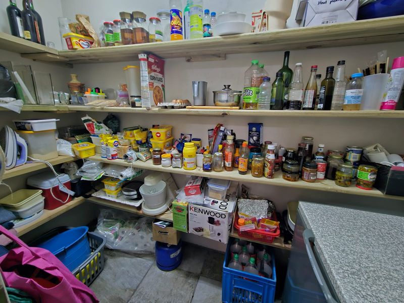 A functional scullery or pantry area featuring extensive open timber shelving for storage and a laminate work surface.