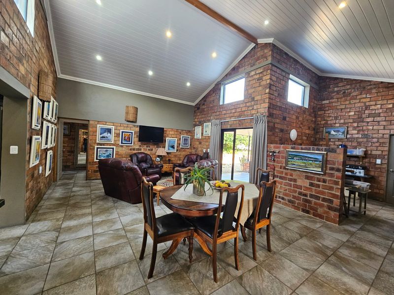Spacious open-plan living and dining area featuring high vaulted ceilings, exposed brick walls, and large sliding doors leading to the outdoor space.
