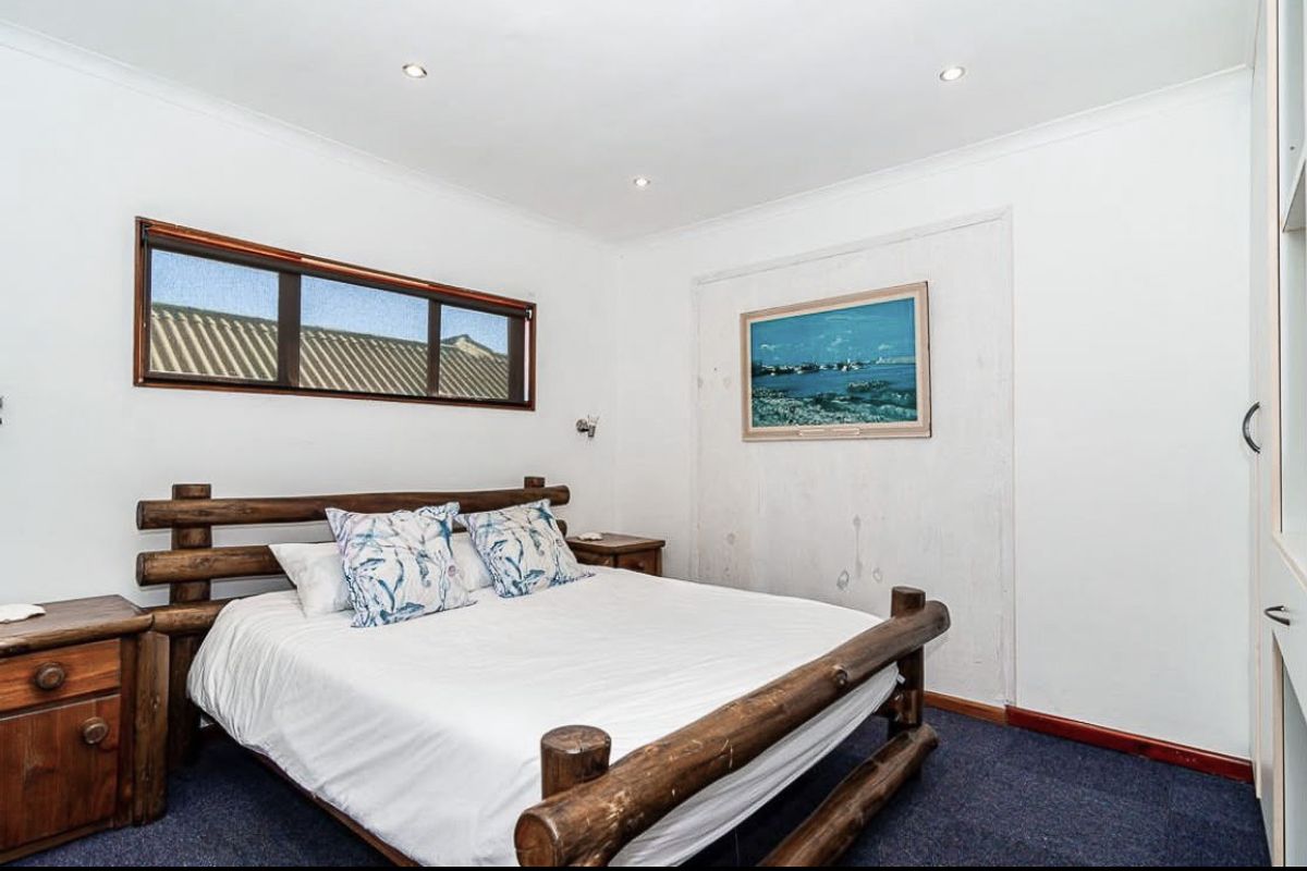 A bedroom featuring recessed downlighting, carpeted flooring, and a built-in wardrobe, with some visible wall imperfections requiring attention.