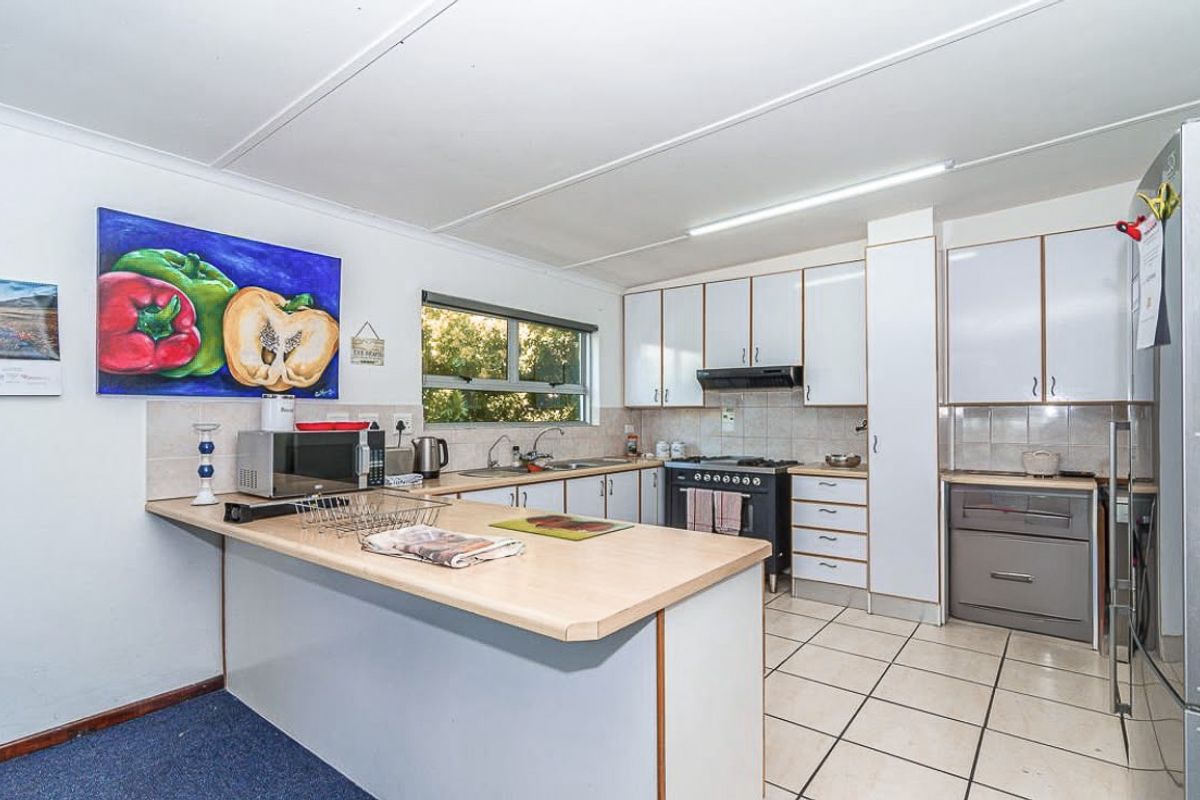 Functional kitchen featuring white cabinetry, laminate countertops, gas stove with extractor fan, and tiled flooring, offering a practical layout for daily meal preparation.