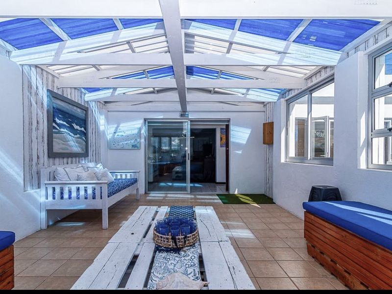 A bright, covered patio area featuring a translucent roof, tiled flooring, and sliding glass doors providing access to the main living space.