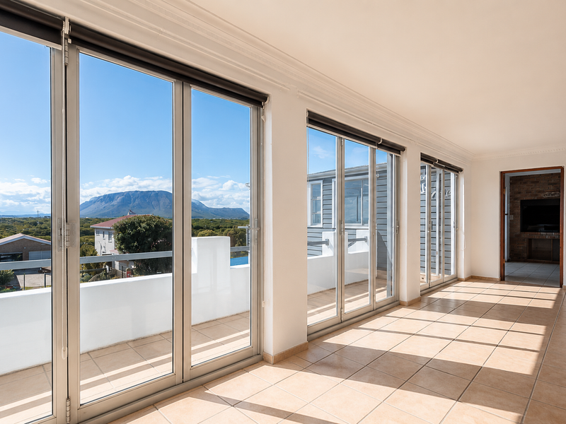 Spacious enclosed balcony featuring large aluminium stackable doors, tiled flooring, and expansive mountain views, offering a bright and versatile living space.