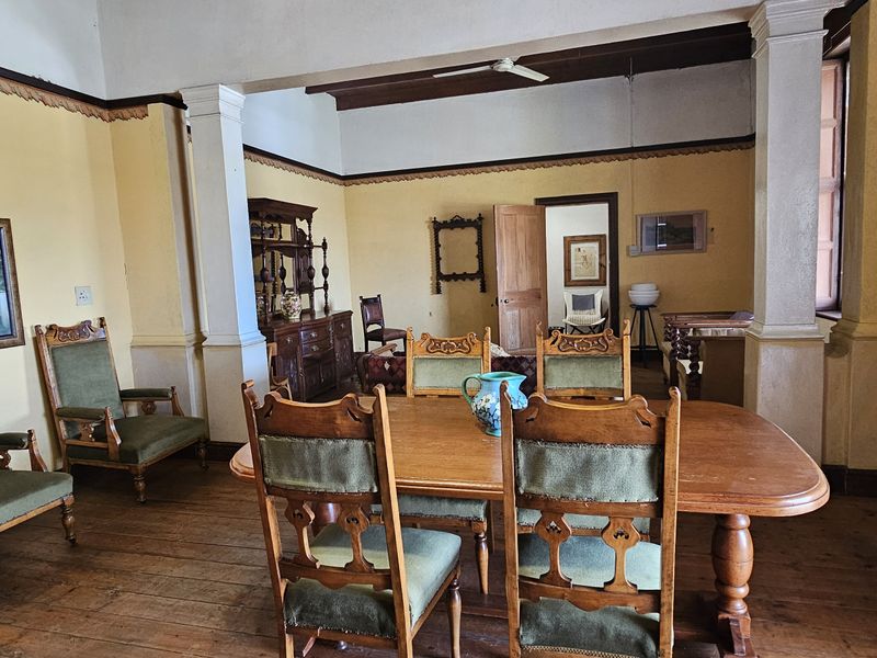 Spacious dining area featuring original timber flooring, structural columns, and high ceilings, offering a classic character aesthetic with potential for modern updates.