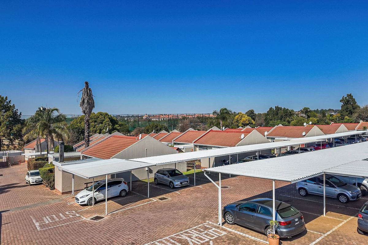 Aerial view of the townhouse complex parking area featuring covered carports and paved driveways.