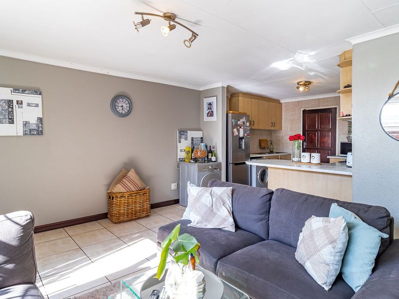 Open plan living area featuring tiled flooring, a functional kitchen with breakfast bar, and integrated cabinetry, creating a versatile and connected living space.