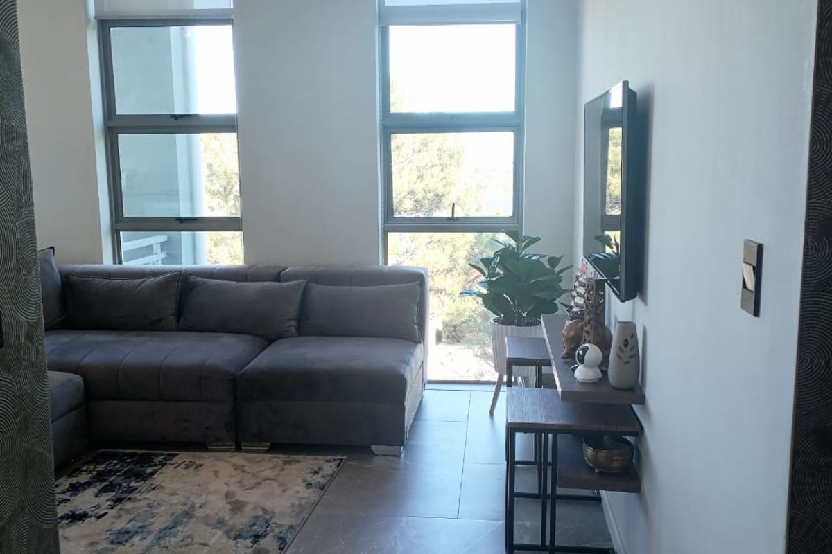 Modern living room featuring large format floor tiles, neutral walls, and dual windows with roller blinds, providing a bright and contemporary atmosphere.