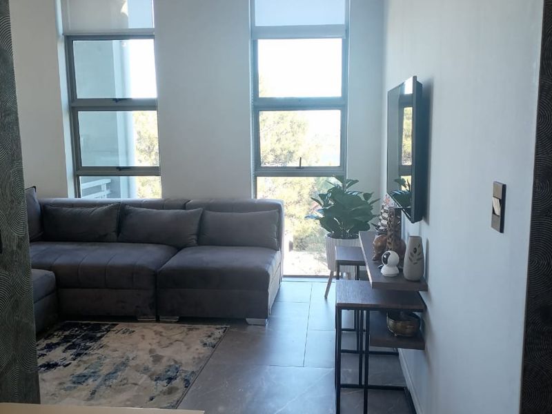 Modern living room featuring large format floor tiles, neutral walls, and dual windows with roller blinds, providing a bright and contemporary atmosphere.