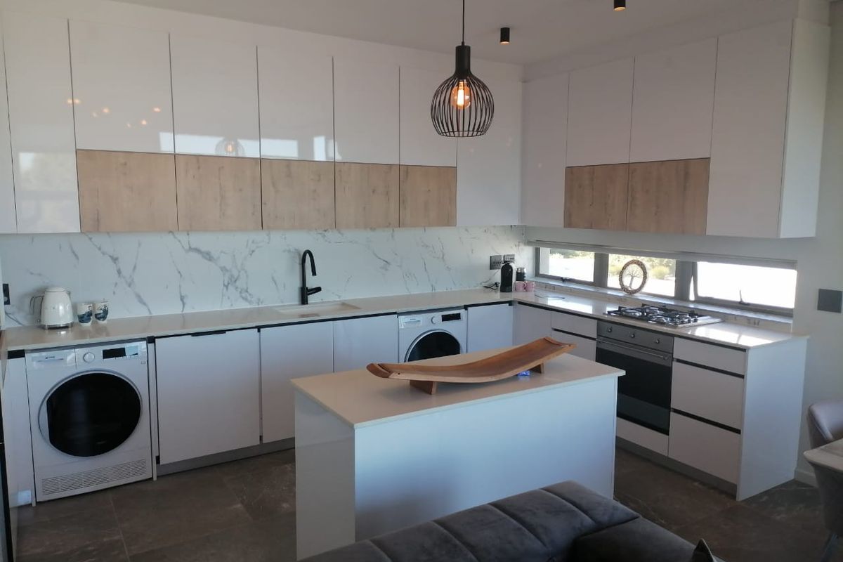 Modern kitchen featuring sleek two-tone cabinetry, marble-look splashback, integrated appliances, and a central island, finished with high-quality fixtures and contemporary lighting.