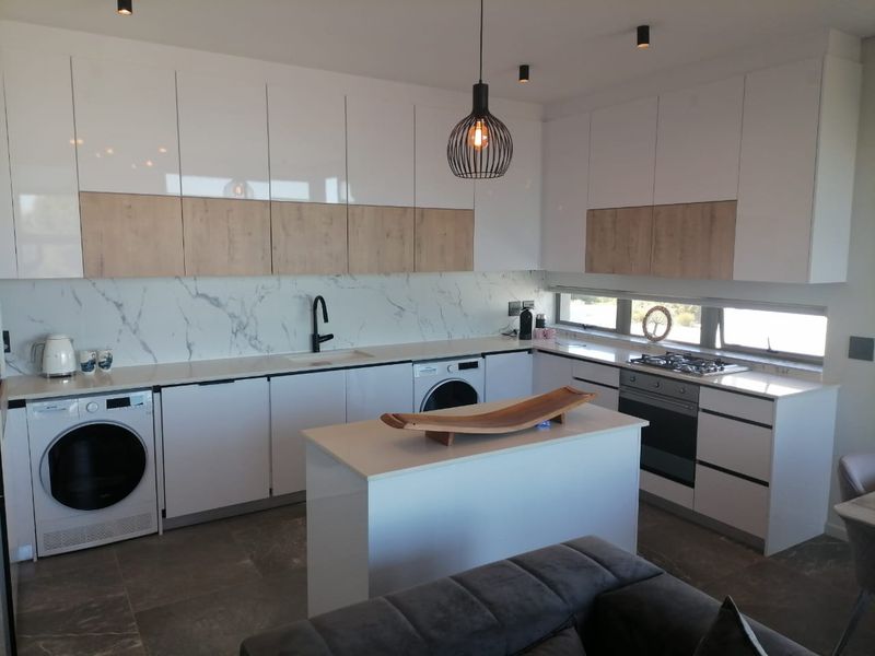 Modern kitchen featuring sleek two-tone cabinetry, marble-look splashback, integrated appliances, and a central island, finished with high-quality fixtures and contemporary lighting.