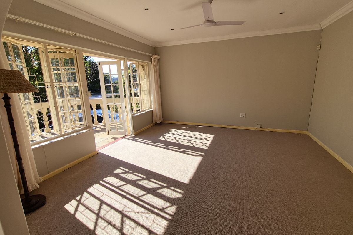 An empty living room featuring carpet flooring, a ceiling fan, and french doors leading to an outdoor balcony area.