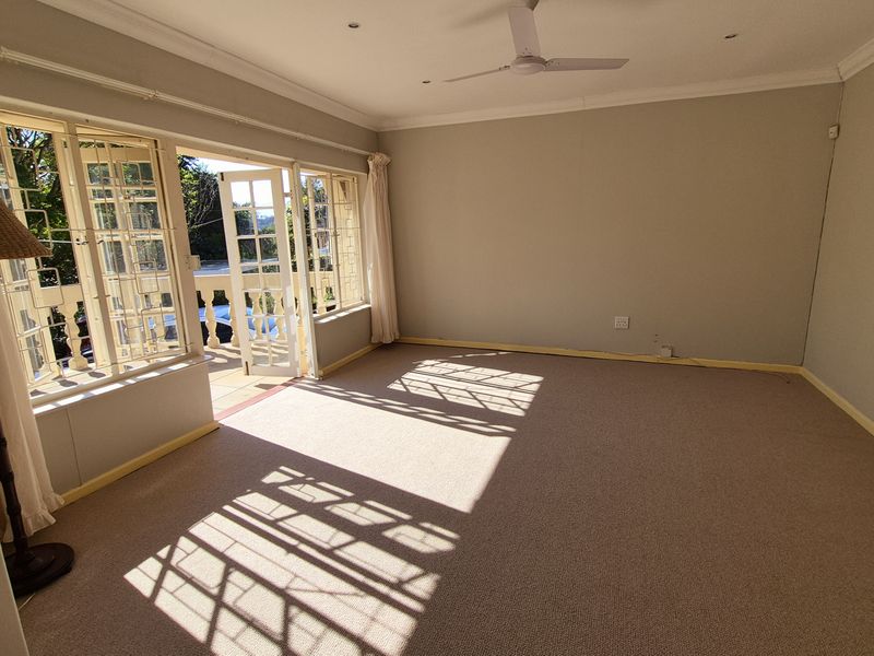 An empty living room featuring carpet flooring, a ceiling fan, and french doors leading to an outdoor balcony area.