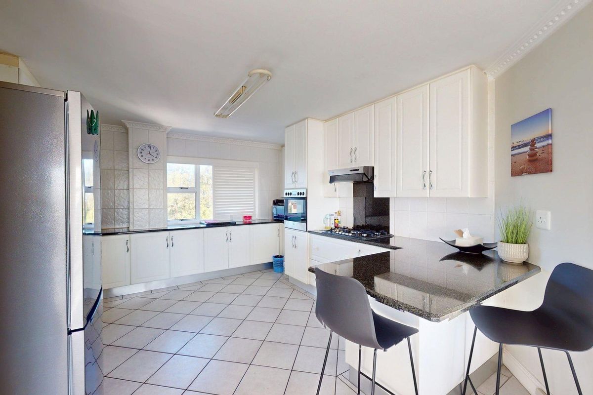A functional kitchen featuring white cabinetry, dark granite countertops, a breakfast bar, and tiled flooring, offering a clean and practical cooking space.