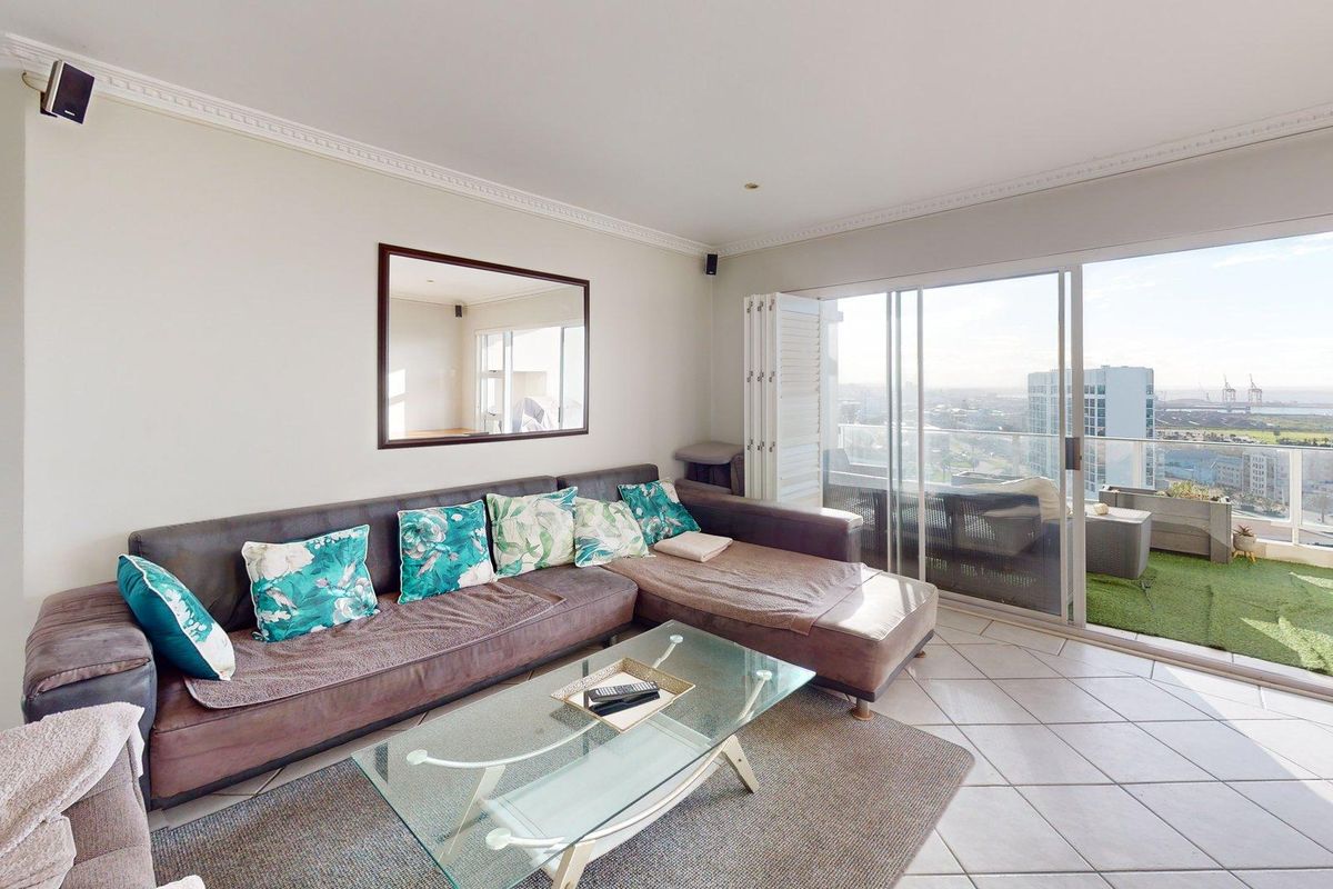Bright living room featuring large sliding glass doors that open onto a balcony, offering expansive city views and abundant natural light.