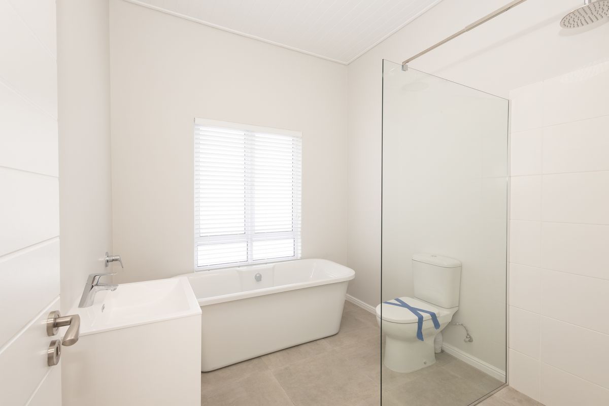 Modern bathroom featuring a clean white aesthetic, a freestanding bathtub, a glass-enclosed shower, and a contemporary vanity basin.