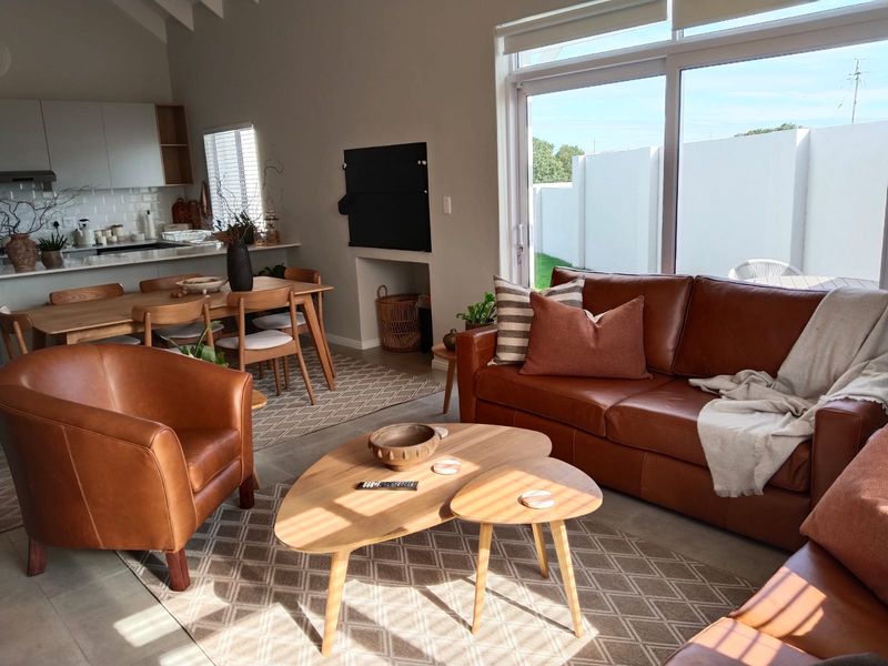Bright open-plan living and dining area featuring a modern kitchen with subway tile backsplash, vaulted ceilings, and large sliding doors leading to the garden.