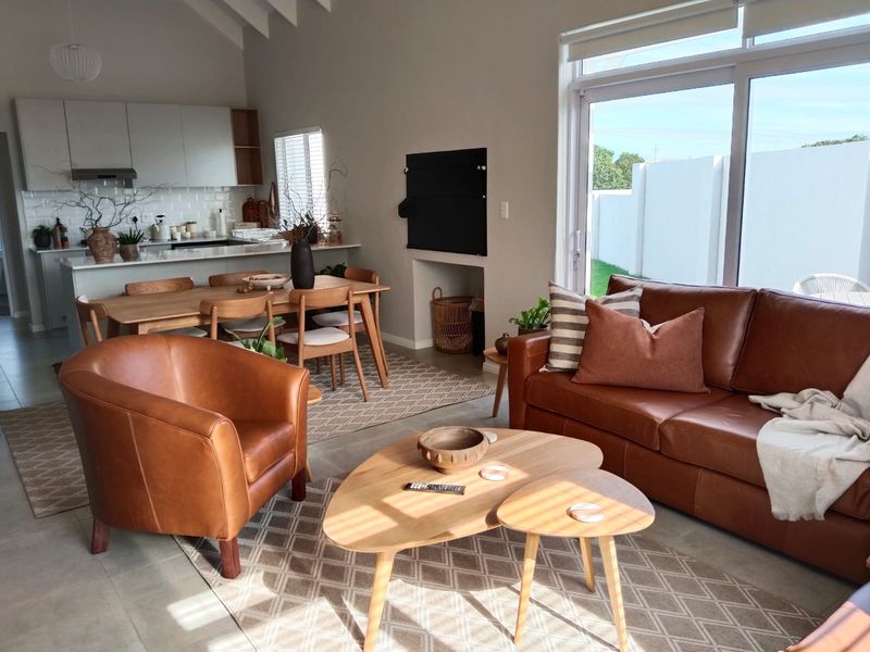 Spacious open-plan living and dining area featuring a modern kitchen with island, vaulted ceilings, and large sliding doors leading to the garden.