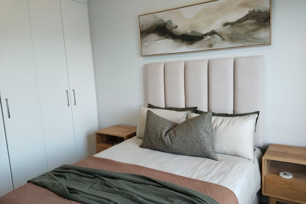 A well-maintained bedroom featuring a neutral color palette, built-in wardrobe storage, and a clean, modern aesthetic.