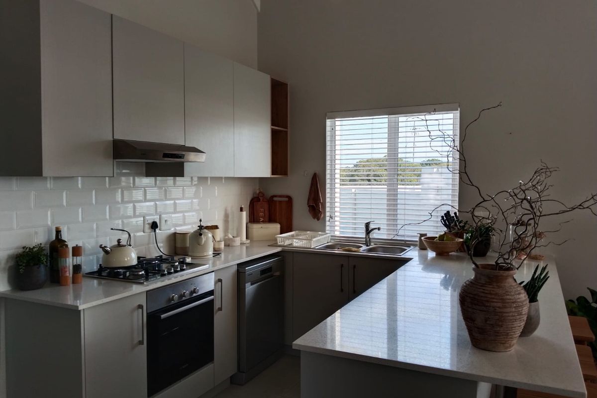Modern kitchen featuring light-toned cabinetry, quartz countertops, subway tile backsplash, gas hob, and integrated oven with a functional breakfast bar layout.