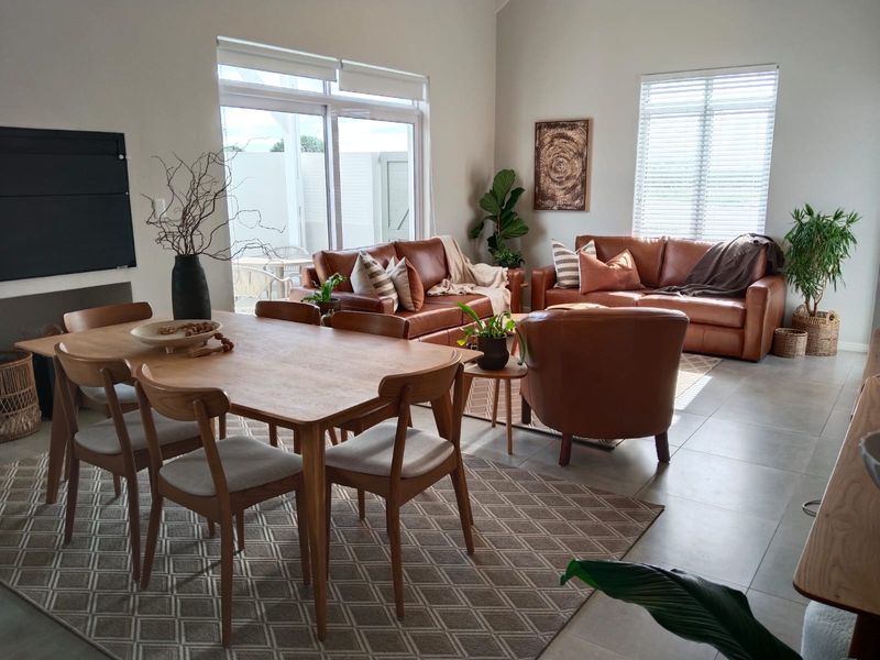 Spacious open-plan living and dining area featuring large format floor tiles, neutral walls, and sliding glass doors providing access to the outdoor patio.
