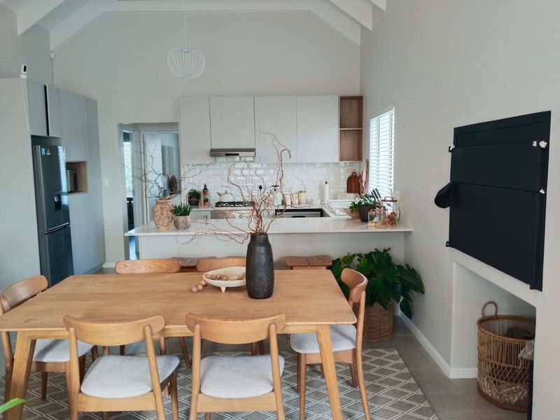 A bright open-plan kitchen and dining area featuring modern cabinetry, stone countertops, a gas hob, and a spacious vaulted ceiling.