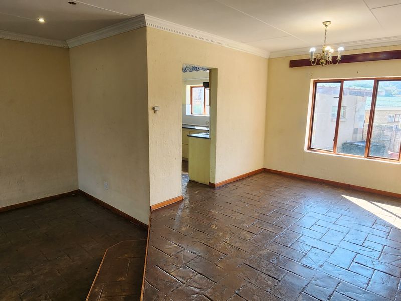 Spacious living area featuring tiled flooring, coved ceilings, and natural light through aluminium windows, offering a blank canvas for interior design.