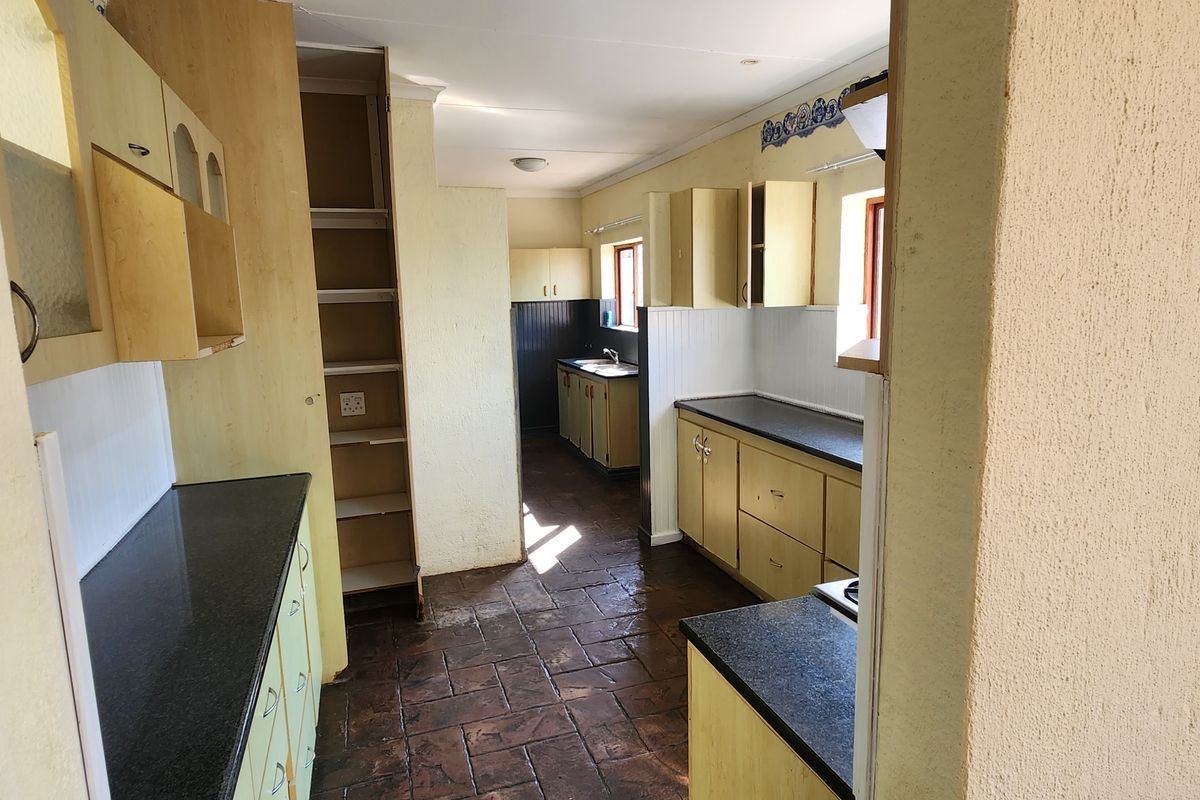 A functional kitchen featuring laminate cabinetry, stone countertops, and tiled flooring, offering a practical layout with ample storage space.