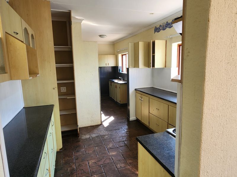 A functional kitchen featuring laminate cabinetry, stone countertops, and tiled flooring, offering a practical layout with ample storage space.