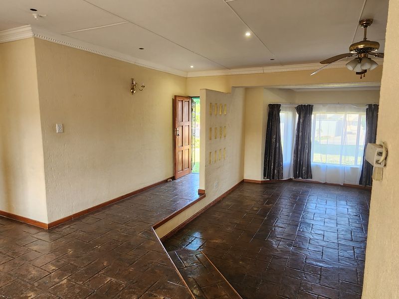 An open-plan living area featuring split-level tiled flooring, recessed lighting, and a ceiling fan, offering a blank canvas for interior design.