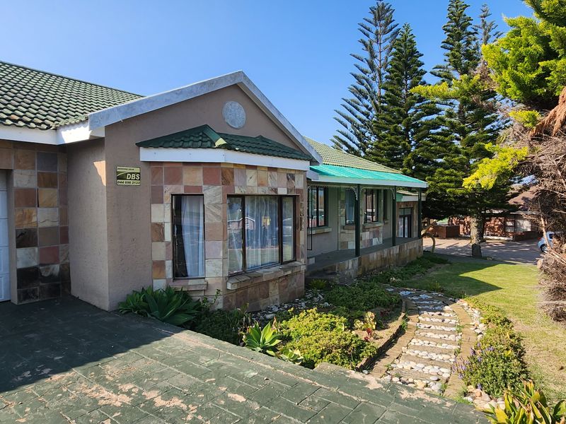 Front exterior view of a house featuring stone cladding, a tiled roof, a single garage, and a landscaped garden with a stone pathway.