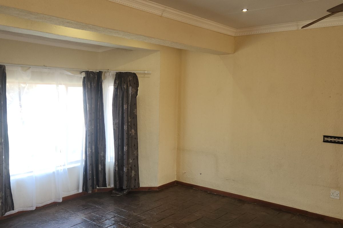 An empty living room featuring tiled flooring, crown molding, and a ceiling fan, with neutral wall finishes ready for a fresh update.