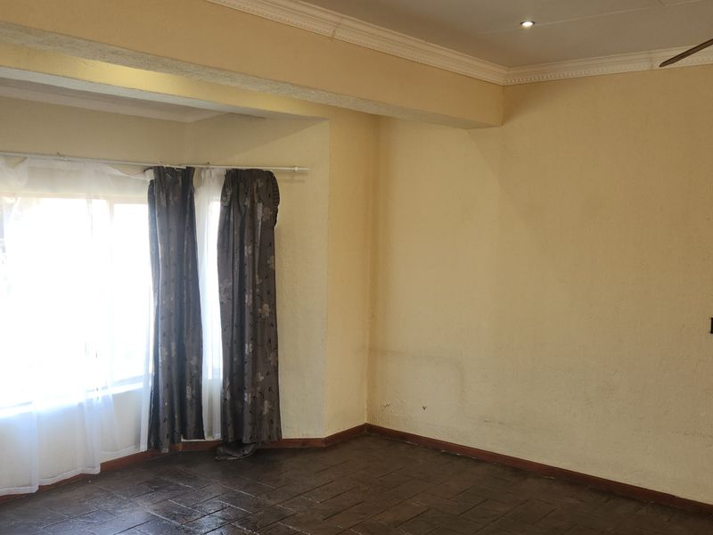 An empty living room featuring tiled flooring, crown molding, and a ceiling fan, with neutral wall finishes ready for a fresh update.