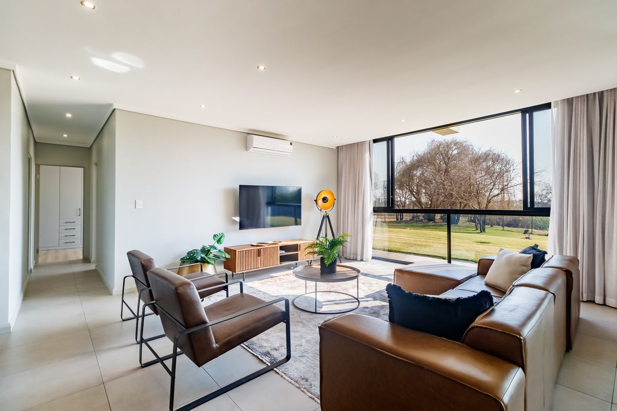 Modern, light-filled living room featuring tiled floors, recessed lighting, a split-system air conditioner, and large sliding glass doors with views of the garden.